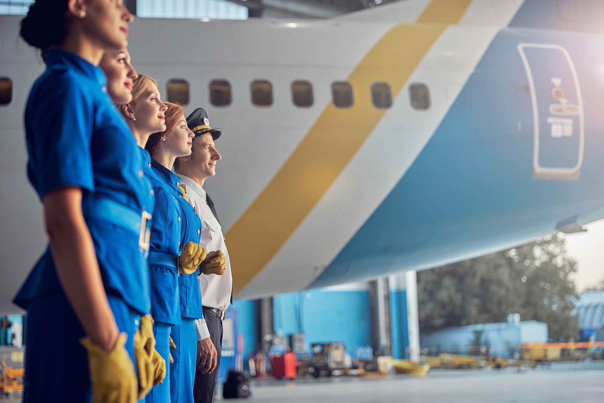 happy-smiling-pilot-and-charming-stewardesses-looking-ahead-in-the-hangar-at-the-airport.jpg